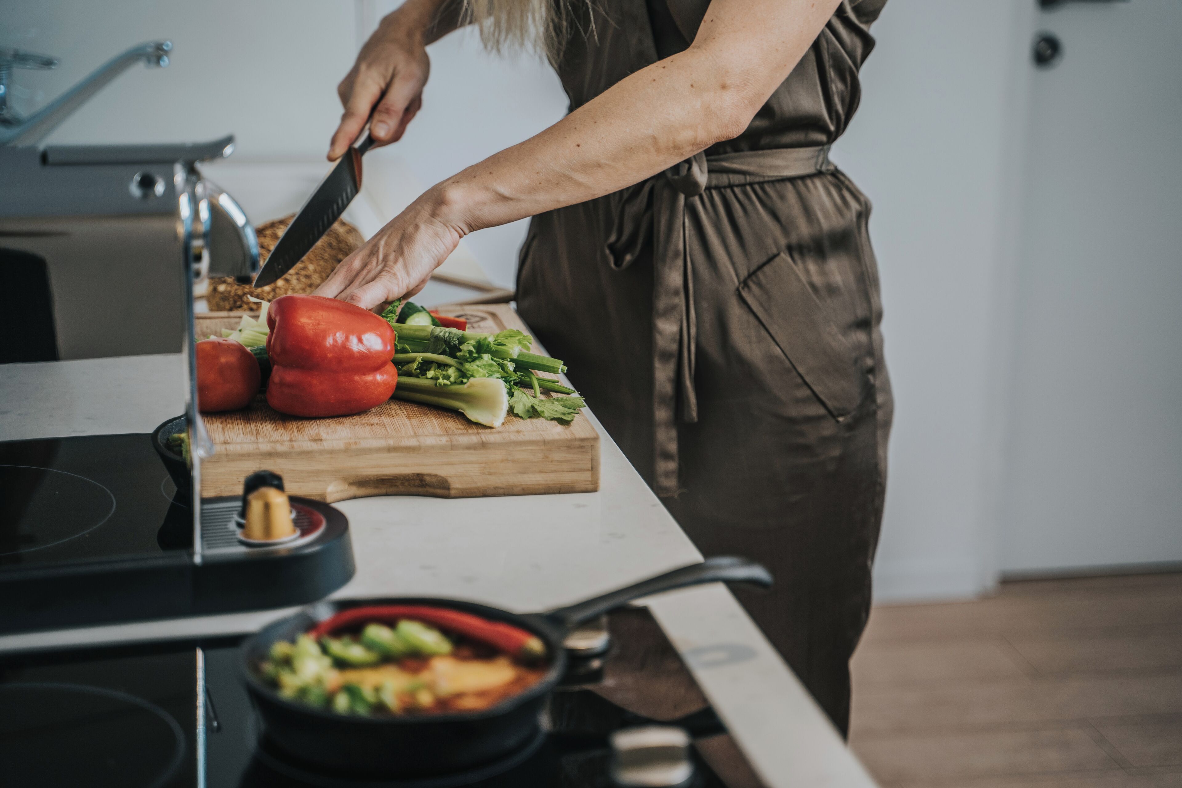 A person chopping vegetables on a wooden cutting board in a kitchen.