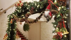 Un escalier décoré de guirlandes de Noël, de pommes de pin et d’un ornement représentant le Père Noël.