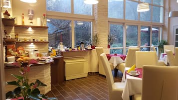 A well-lit breakfast area with a counter, dining tables, and chairs.