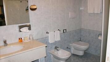 A bathroom with a sink, bidet, toilet, and a mirror.