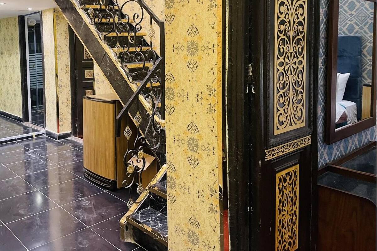 A staircase with ornate black railings and a patterned yellow wall.