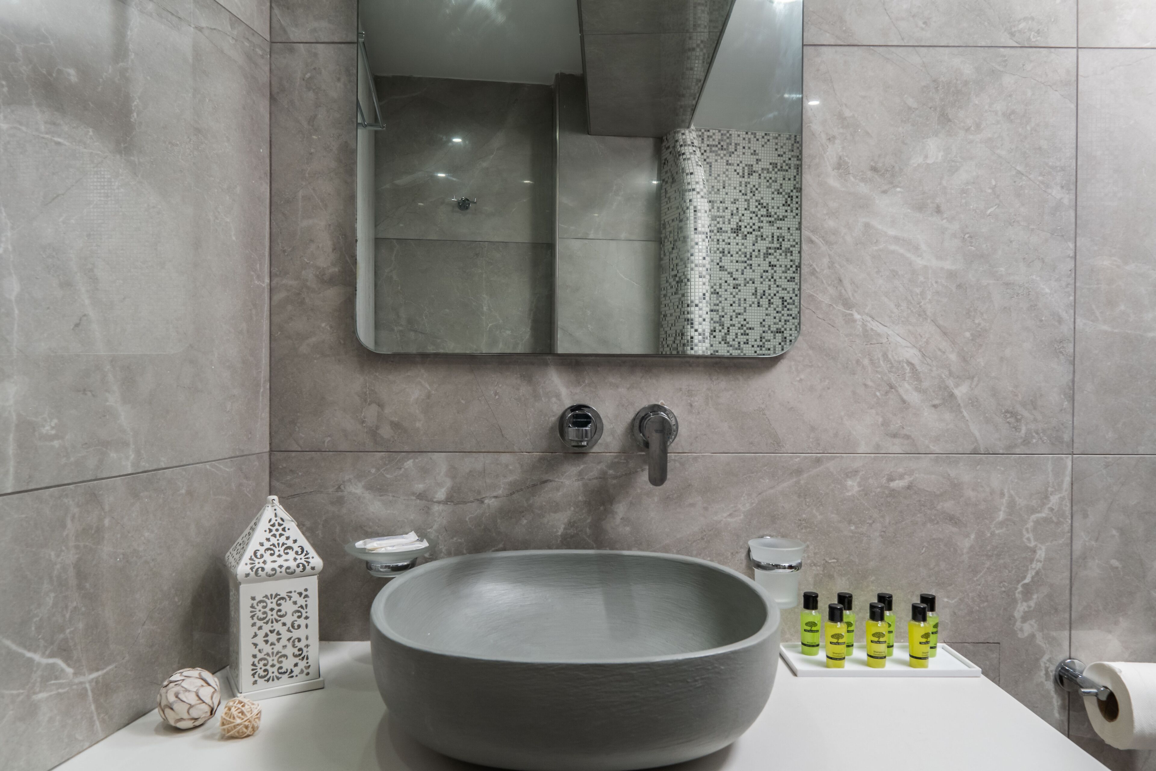 A bathroom with a large vessel sink, a mirror, a toilet, and toiletries on the counter.