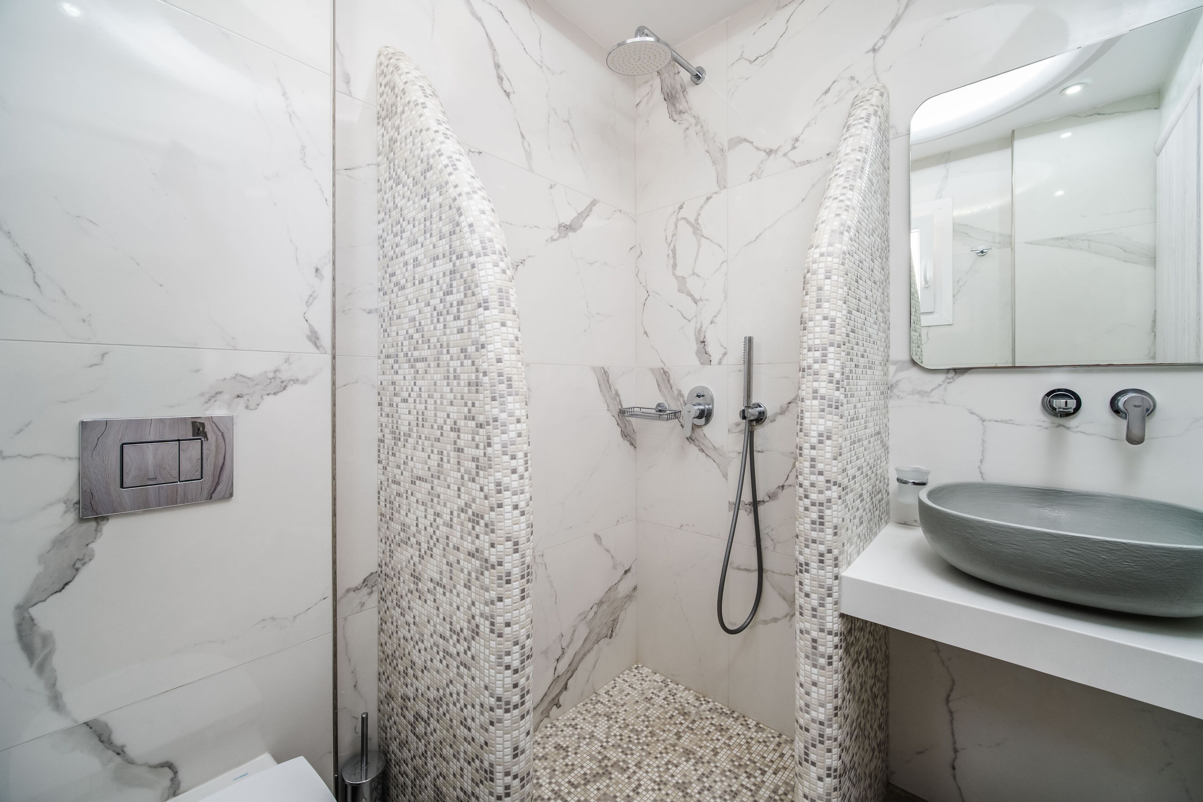 A modern bathroom with a shower, a sink, and a mirror.