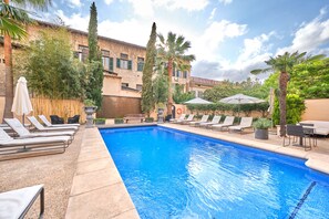 Una piscina al aire libre, sombrillas, tumbonas