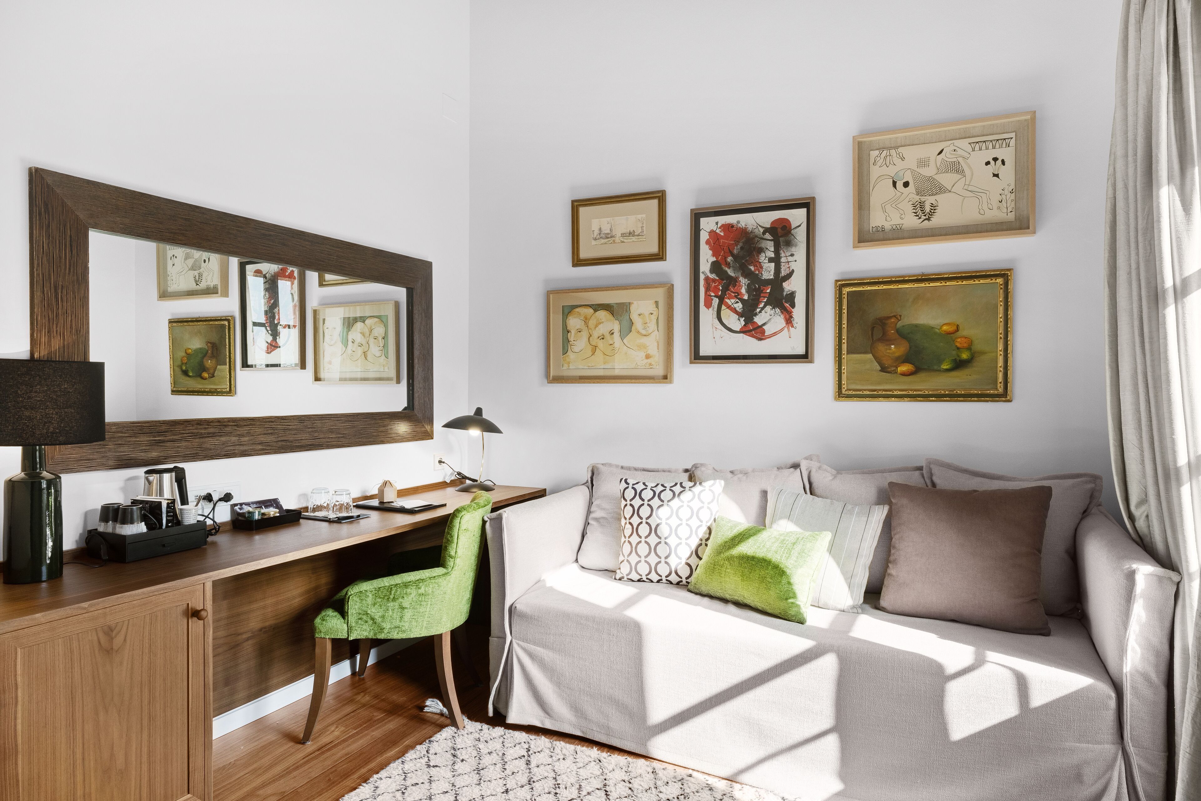 A modern room with a wooden desk, green chair, and a sofa with patterned cushions.