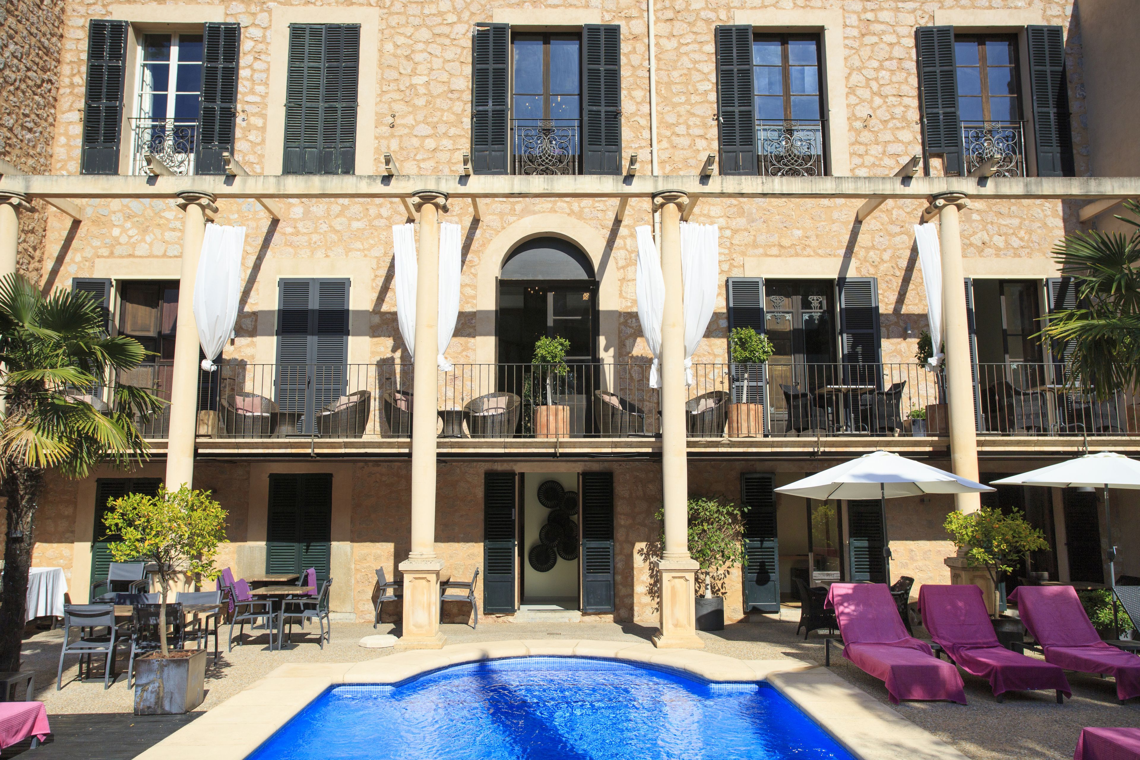Un hotel con piscina, mobiliario de exterior y balcones.