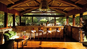 A bar area with wooden beams, a bar counter, and several chairs. - Rio Sagrado, A Belmond Hotel, Sacred Valley (Urubamba)