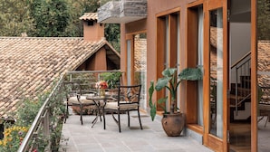 A modern building with large windows, a balcony with outdoor furniture, and a view of the surrounding hills. - Rio Sagrado, A Belmond Hotel, Sacred Valley (Urubamba)