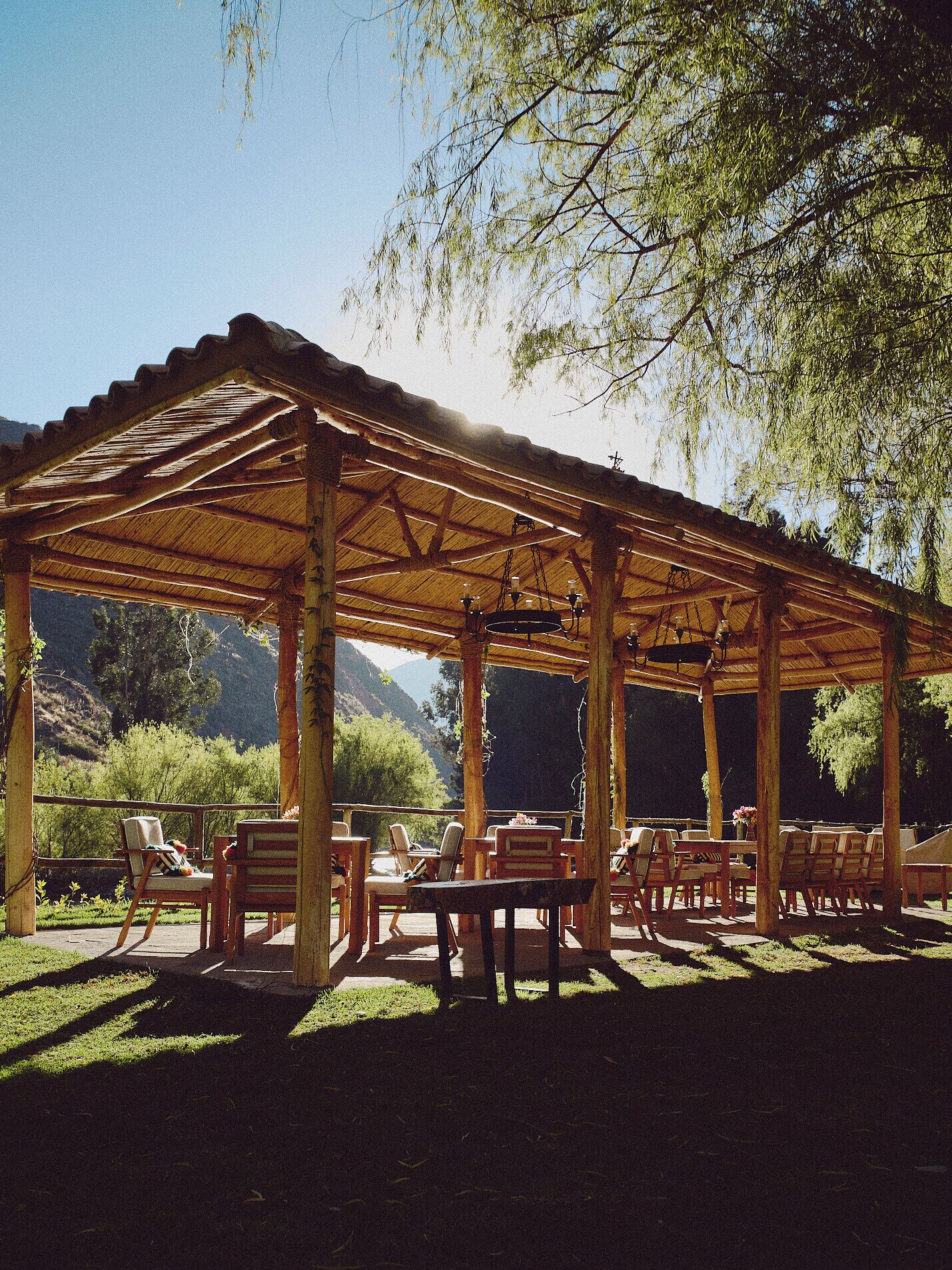 Un pabellón al aire libre con techo de madera y varias zonas de estar.