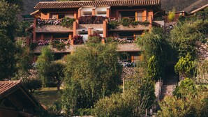 A multi-story building with balconies, surrounded by lush greenery and mountains in the background. - Rio Sagrado, A Belmond Hotel, Sacred Valley (Urubamba)