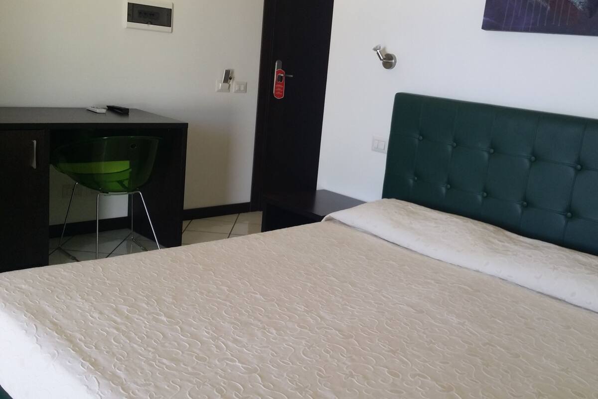 A bedroom with a bed, a desk, and a chair.