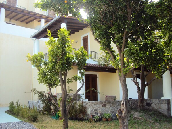A building with a stone wall, potted plants, and a clear sky.