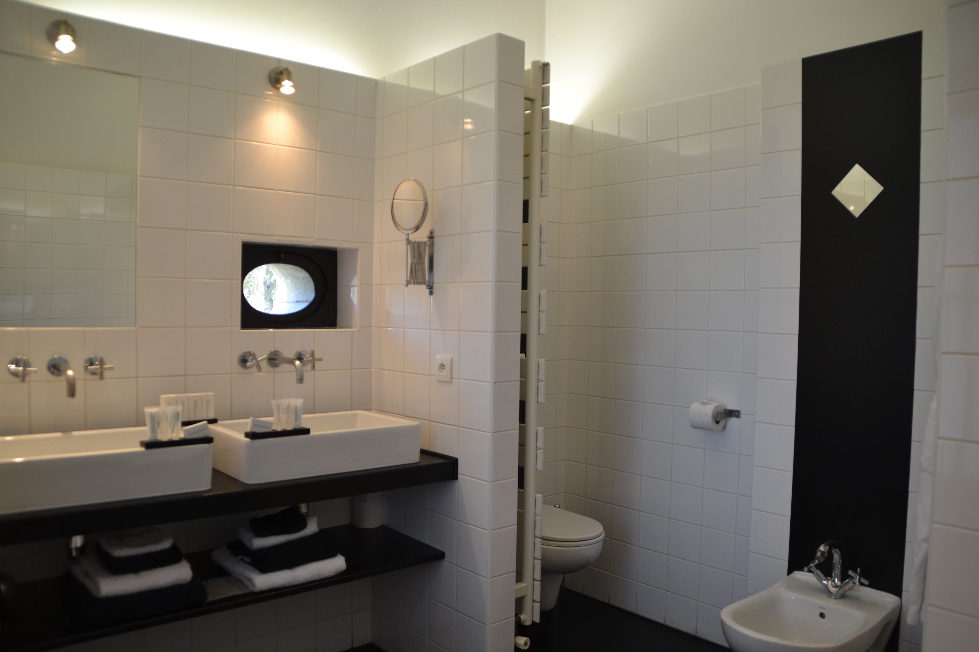 A modern bathroom with two sinks, a bidet, and a mirror.