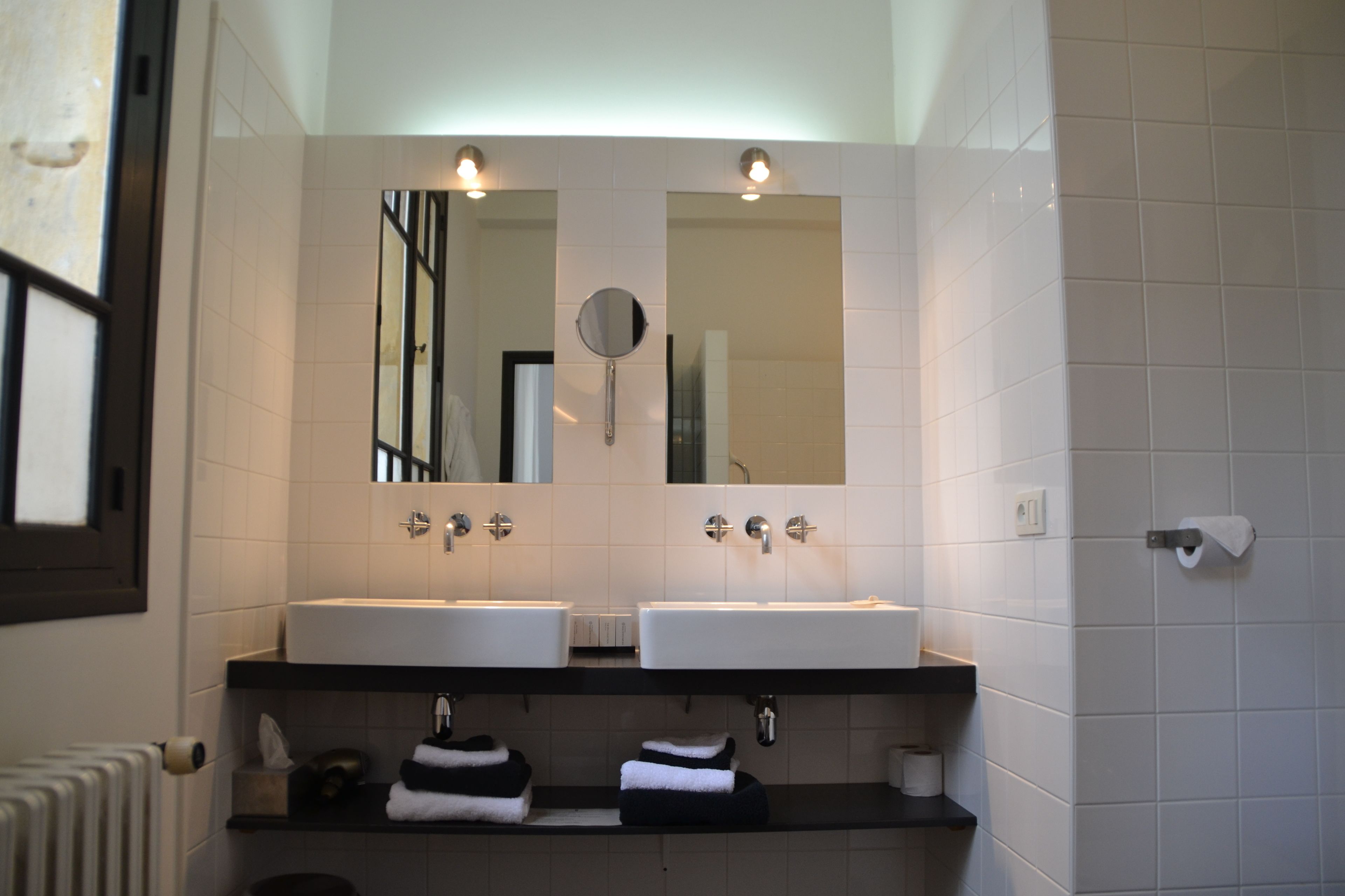A bathroom with two sinks, a mirror, and a towel rack.