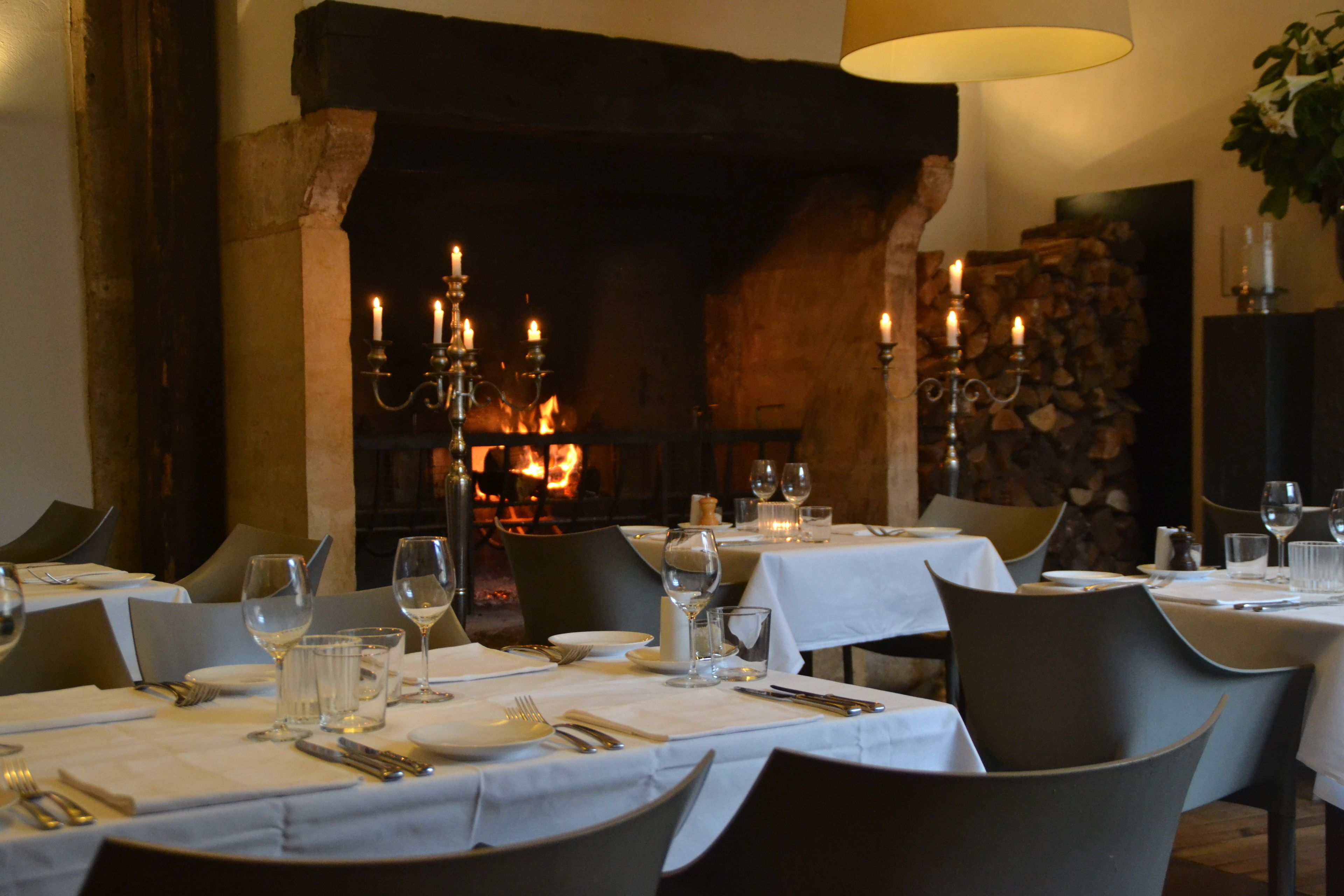 Un restaurante con mesas dispuestas para comer, una chimenea al fondo y una pared de piedra.