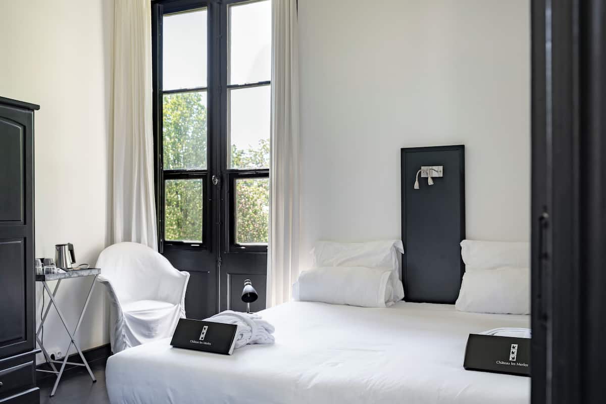 Habitació d'hotel amb un llit, escriptori amb un ordinador portàtil, una cadira i un armari.