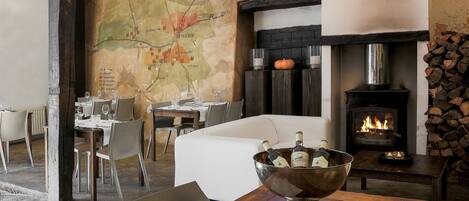A cozy dining area with a map on the wall, a fireplace, and a table with a wine bucket.