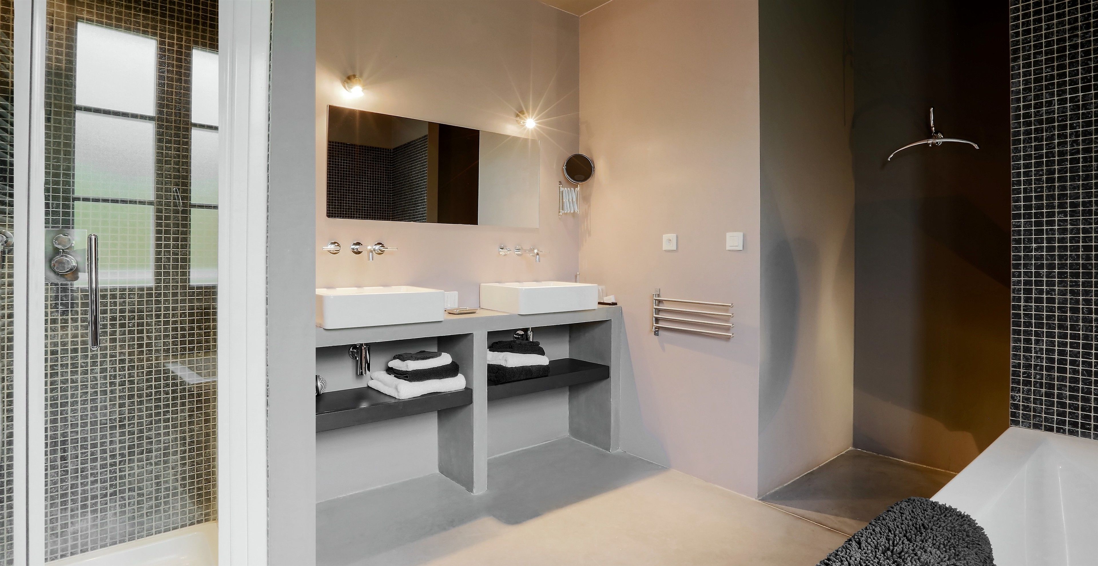 A modern bathroom with two sinks, a large mirror, and a shower area.