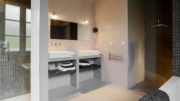 A modern bathroom with two sinks, a large mirror, and a shower area.