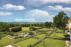 A landscaped garden with a swimming pool, sun loungers, and umbrellas.