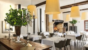 En restaurant med træborde, levende lys som midtpunkt og hængende lamper.