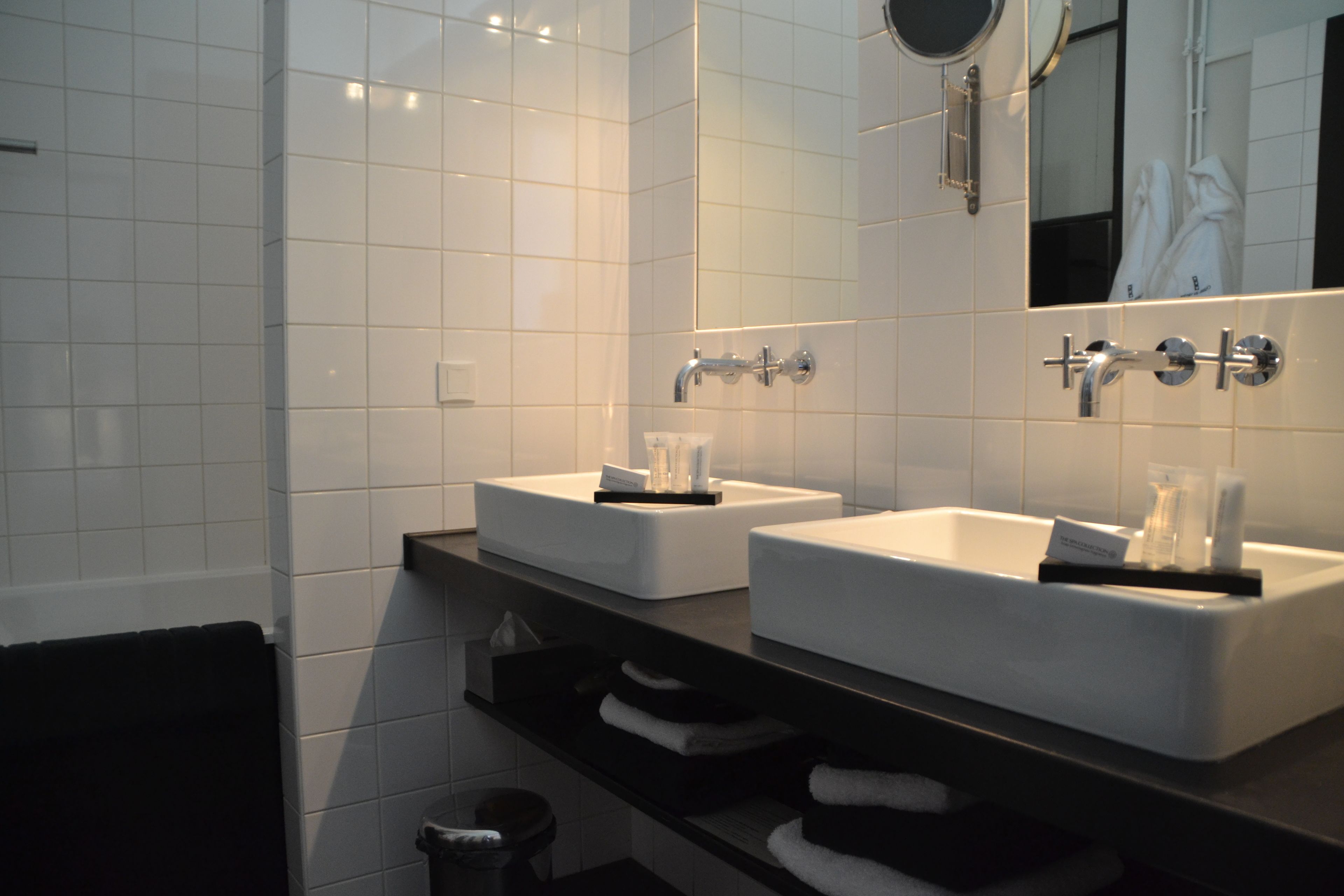 Un baño moderno con dos lavabos, un espejo y un perchero para toallas.
