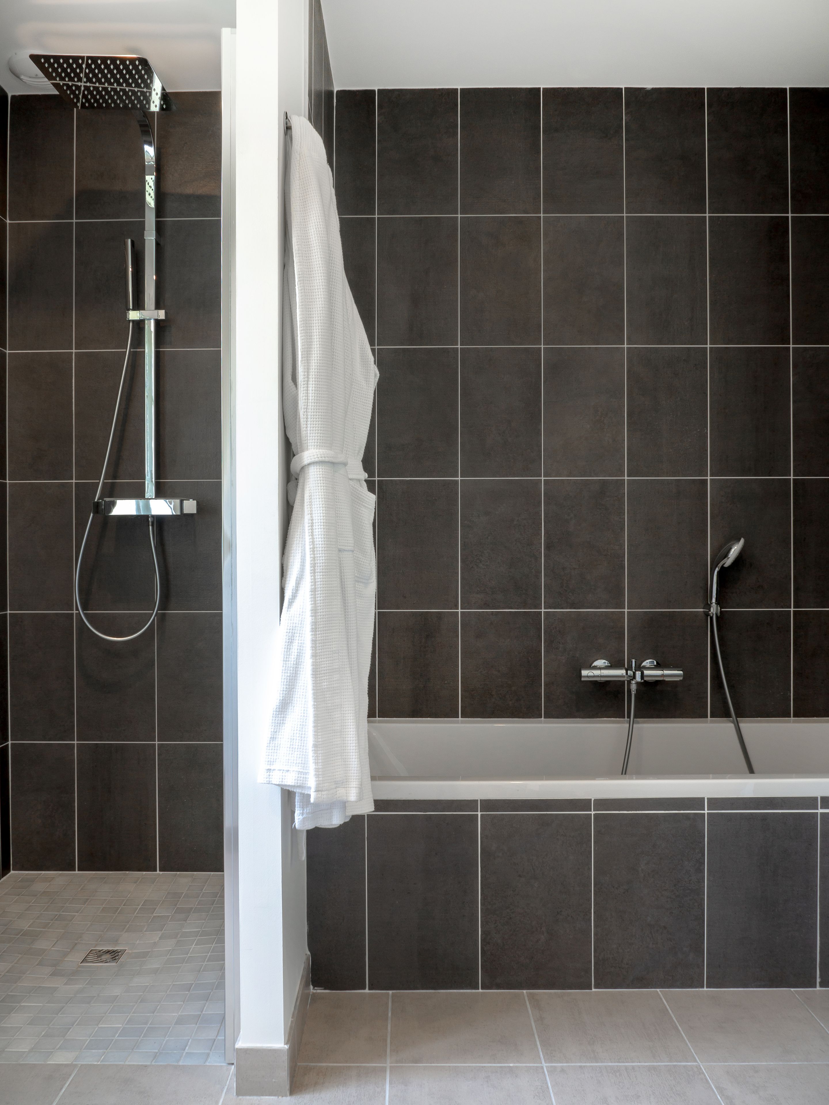 A modern bathroom with a bathtub, shower, and a towel rack with a white towel.