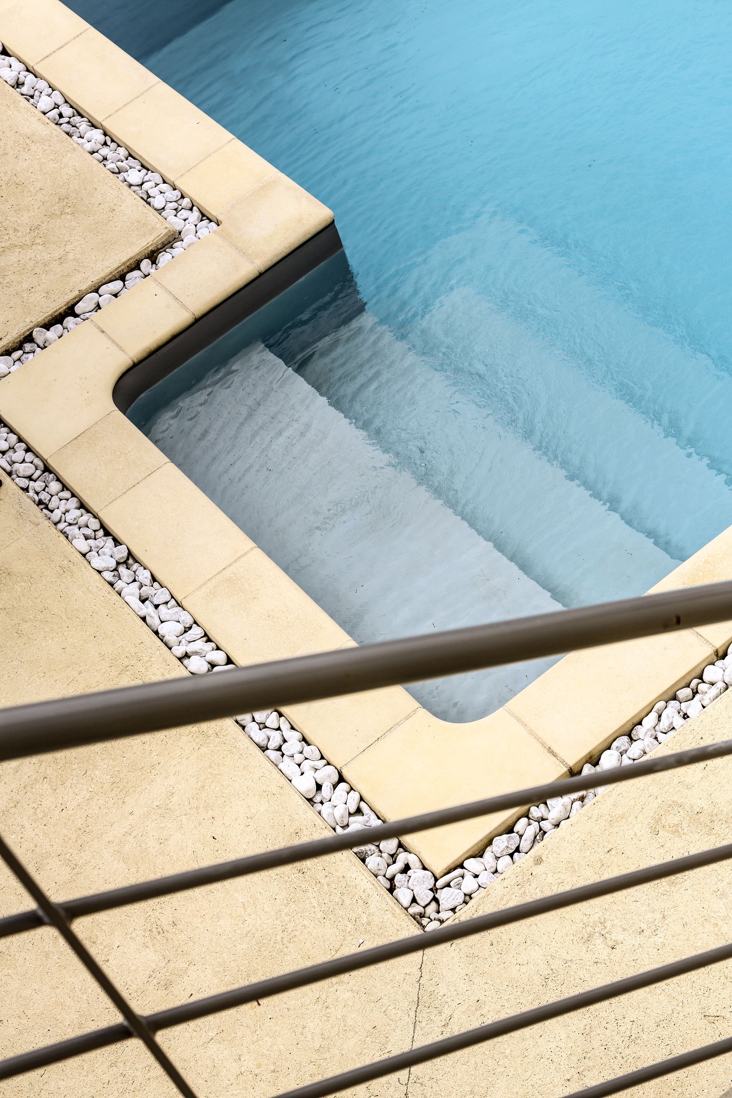 A pool with a stone border and steps leading into it.