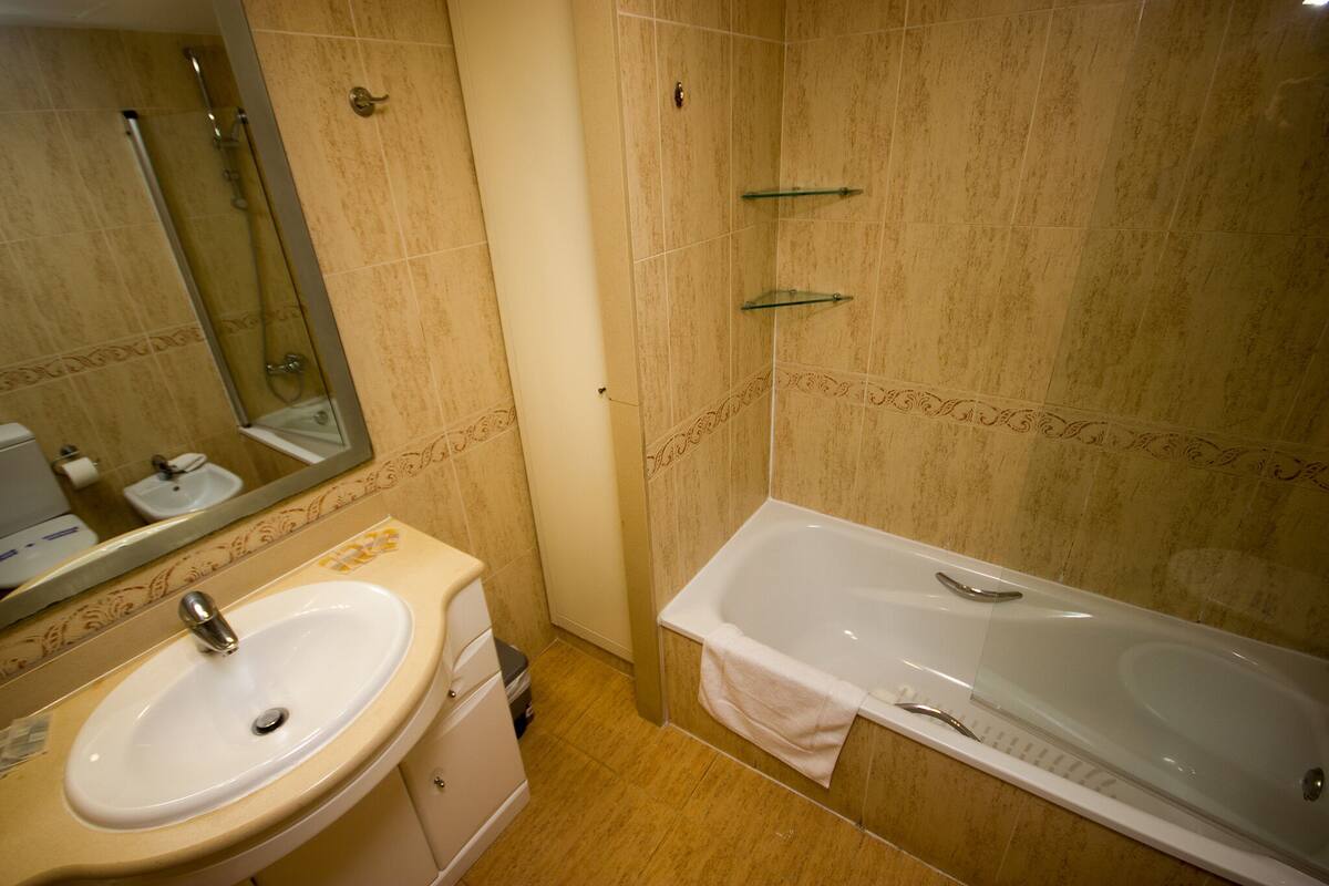 A bathroom with a sink, mirror, and bathtub.