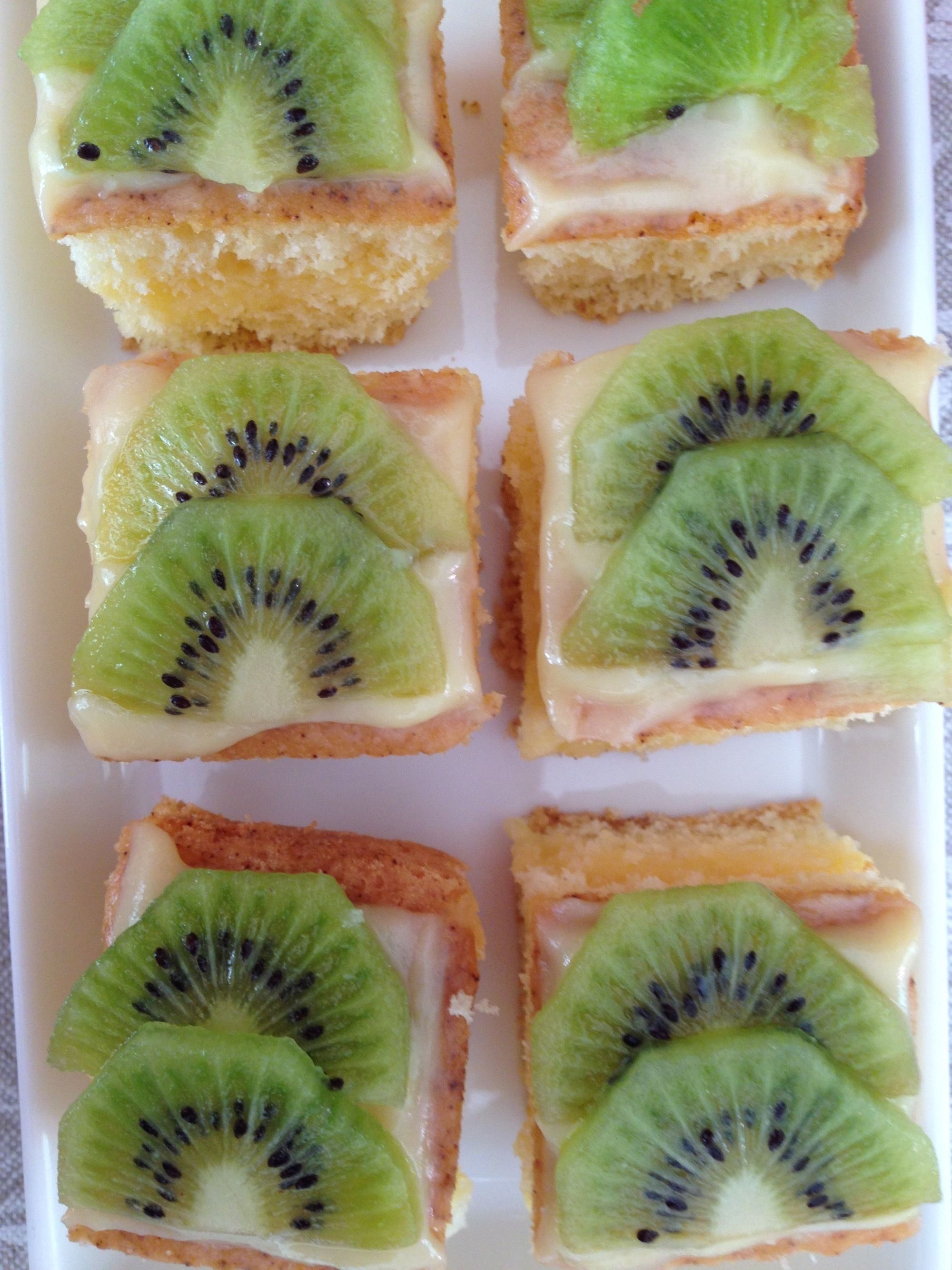 A tray of square pastries topped with kiwi slices and a creamy filling.