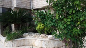 A landscaped garden with a variety of plants and a curved stone bench. - Hotel Marom (Haifa)