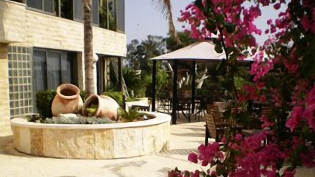A circular water feature with two large pots, surrounded by a paved area with outdoor seating and a pergola. - Hotel Marom (Haifa)