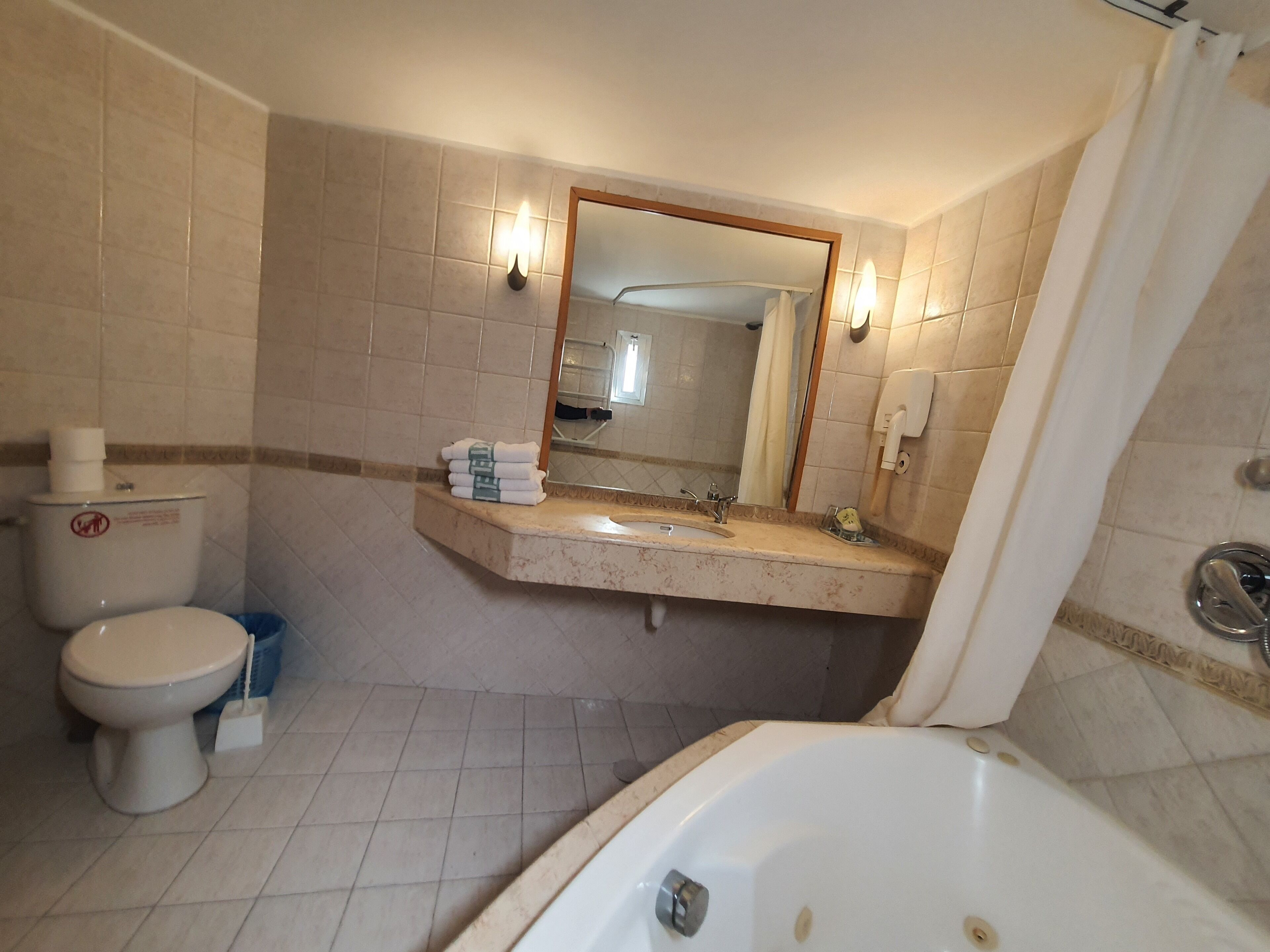 A bathroom with a toilet, sink, mirror, and bathtub.