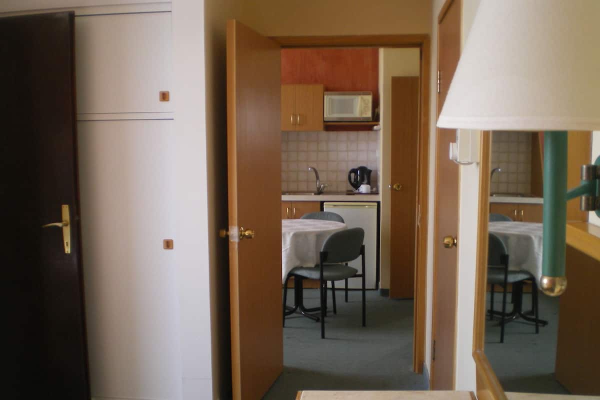 A compact kitchen with a microwave, a coffee maker, and a dining area with two chairs.