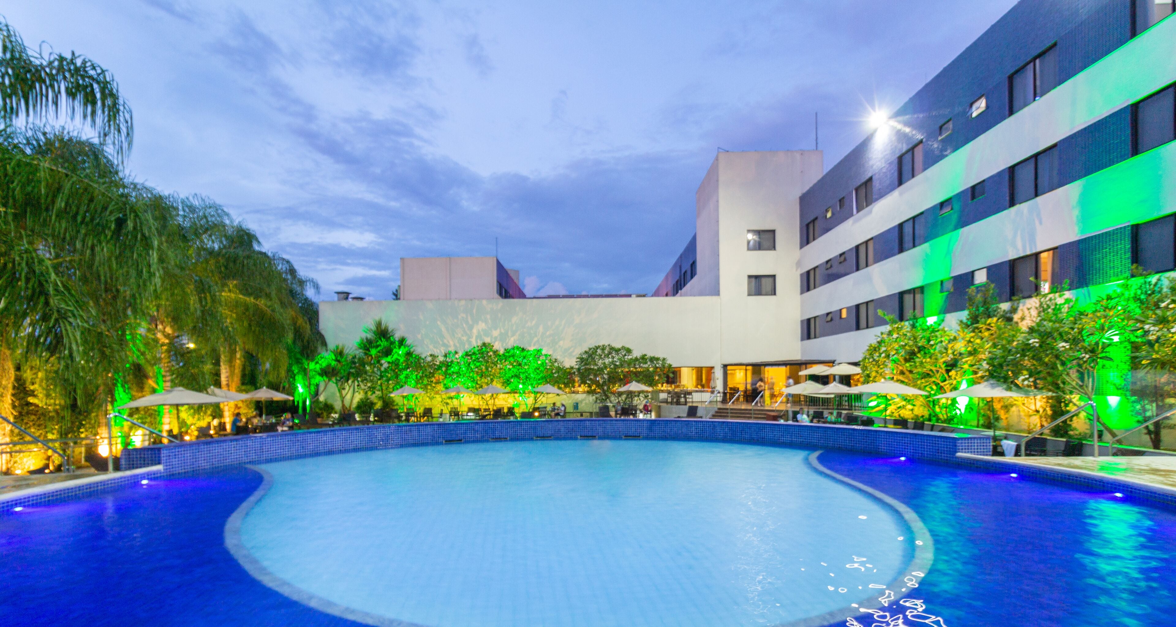 A swimming pool with a curved edge, surrounded by a building with multiple floors and balconies.