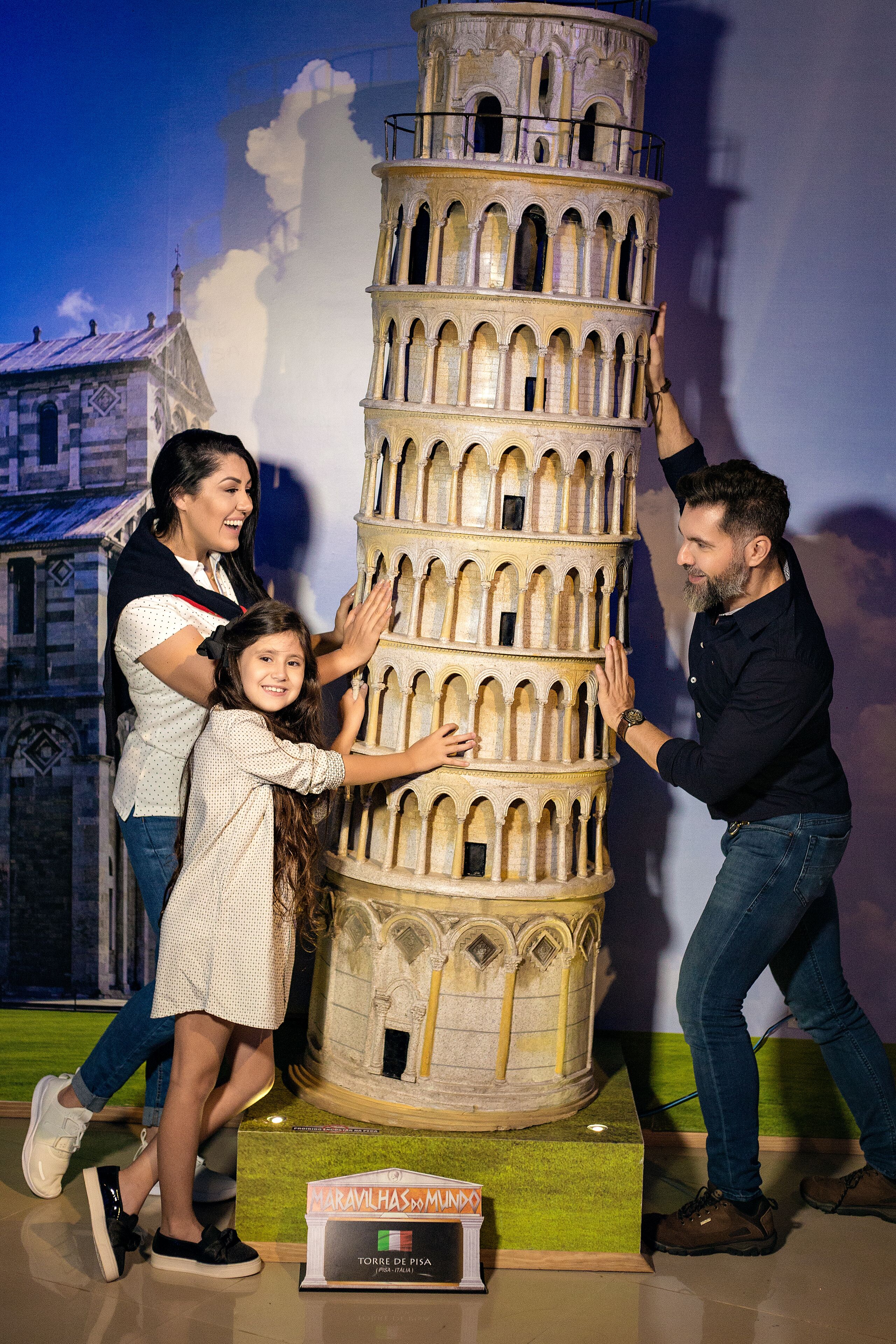 A model of the Leaning Tower of Pisa with people interacting with it.