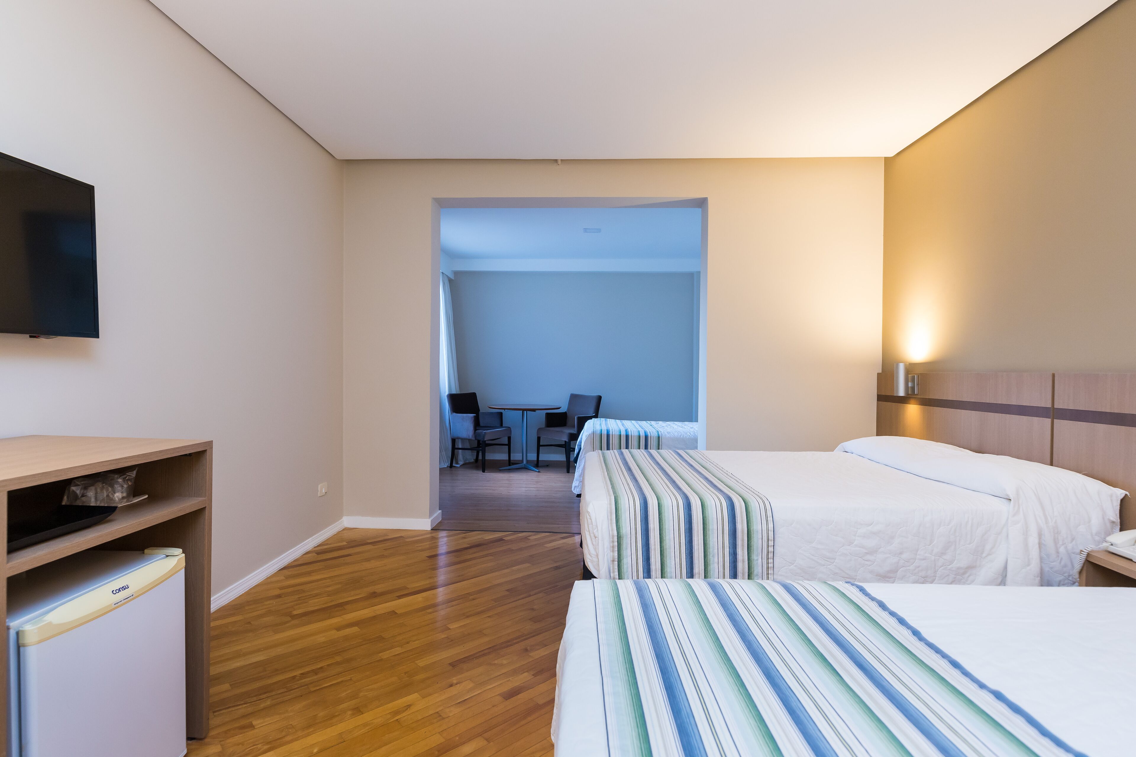 Une chambre d’hôtel avec deux lits, une télévision, un bureau et une chaise.