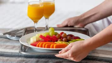 A breakfast tray with sliced fruits, a plate of fruit, and two glasses of orange juice.