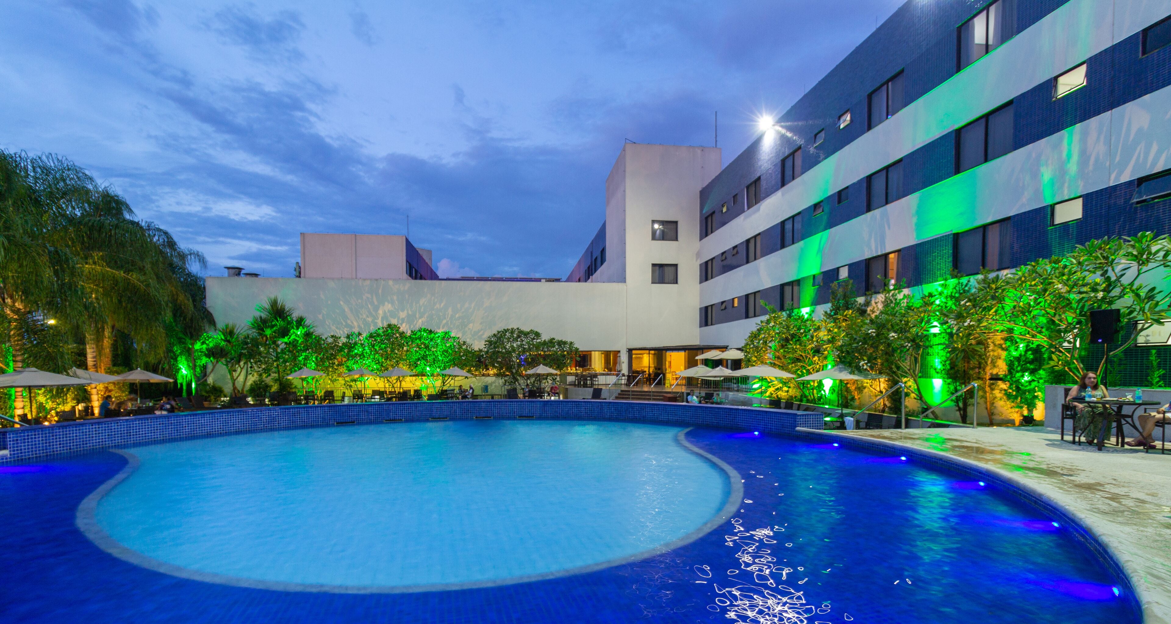 A swimming pool with a curved edge, surrounded by outdoor seating areas and trees.