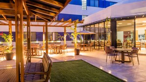 Un patio al aire libre con pérgolas de madera, asientos y mesas.