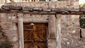 Um edifício de pedra com porta de madeira, piscina com água corrente e uma fonte de pedra.