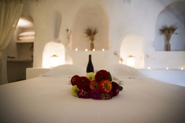 A bed with a floral arrangement in a room with white walls and arched windows. - Les Maisons de Cappadoce (Nevsehir)