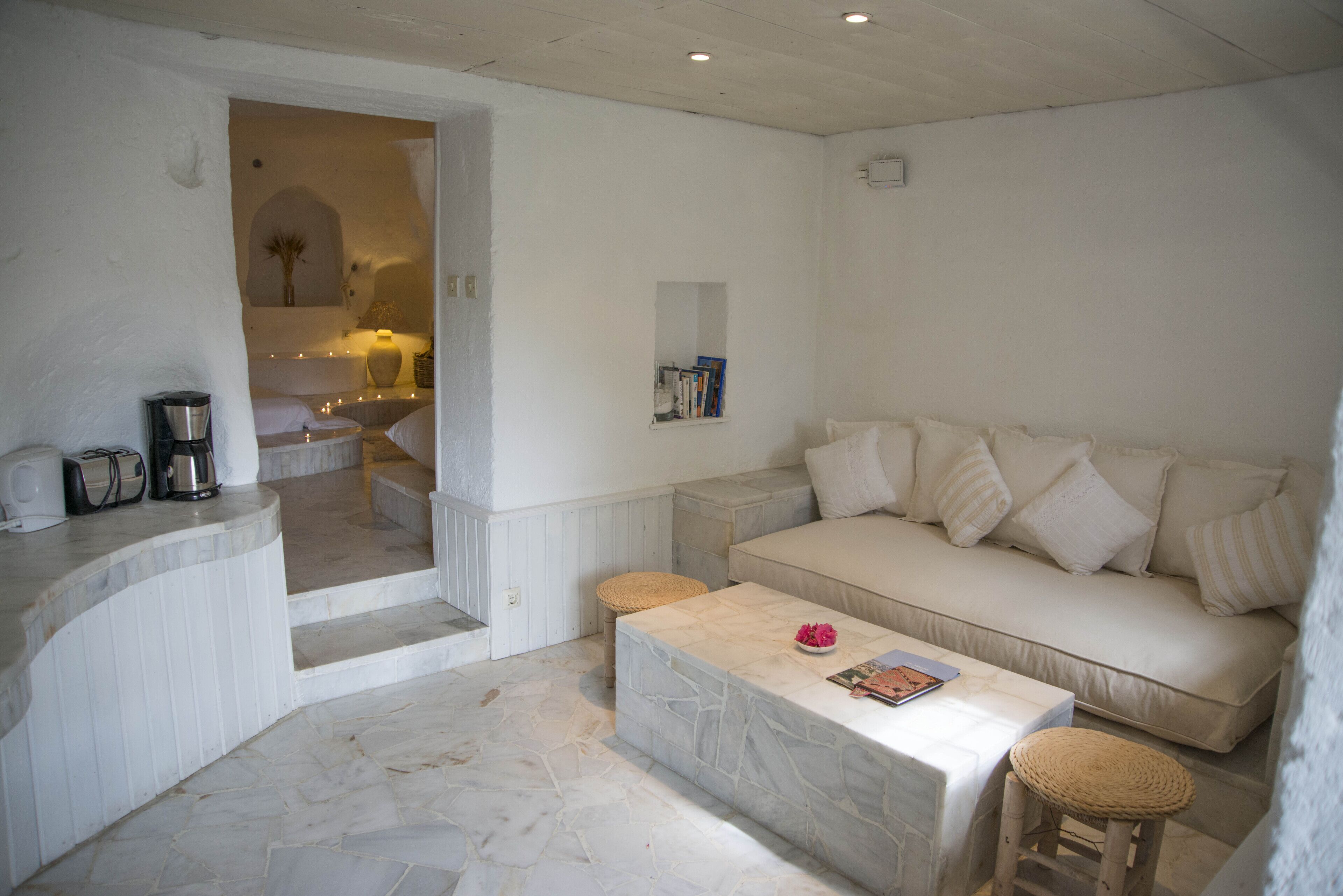 Una sala de estar con un sofá blanco, una mesa de centro y un pequeño rincón de descanso.