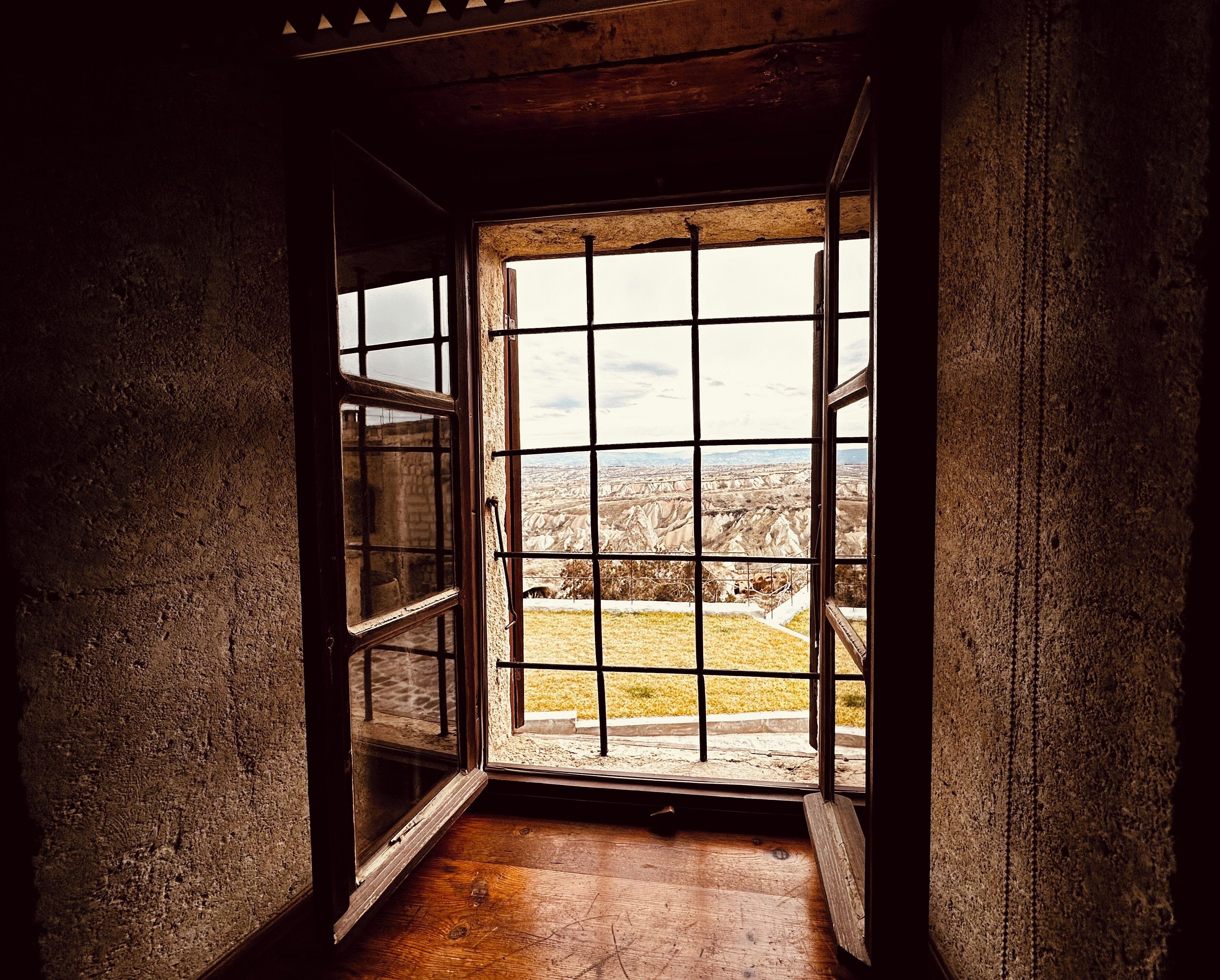 An open window with a view of a rugged landscape.