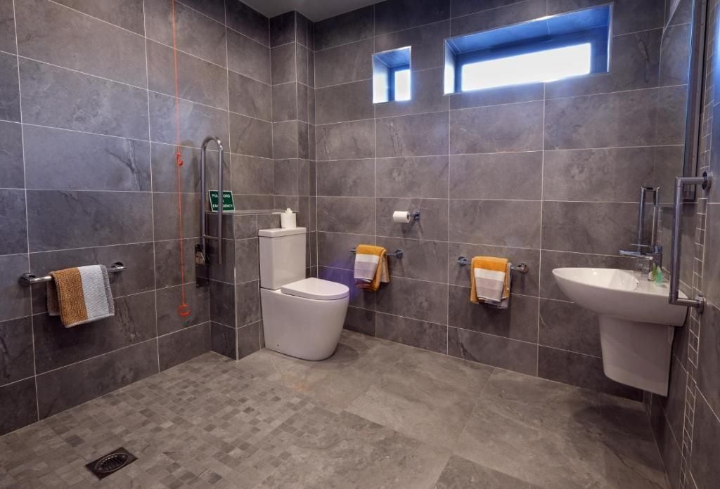 Une salle de bain moderne équipée de toilettes, d’un bidet et d’un lavabo, le tout agrémenté de porte-serviettes.