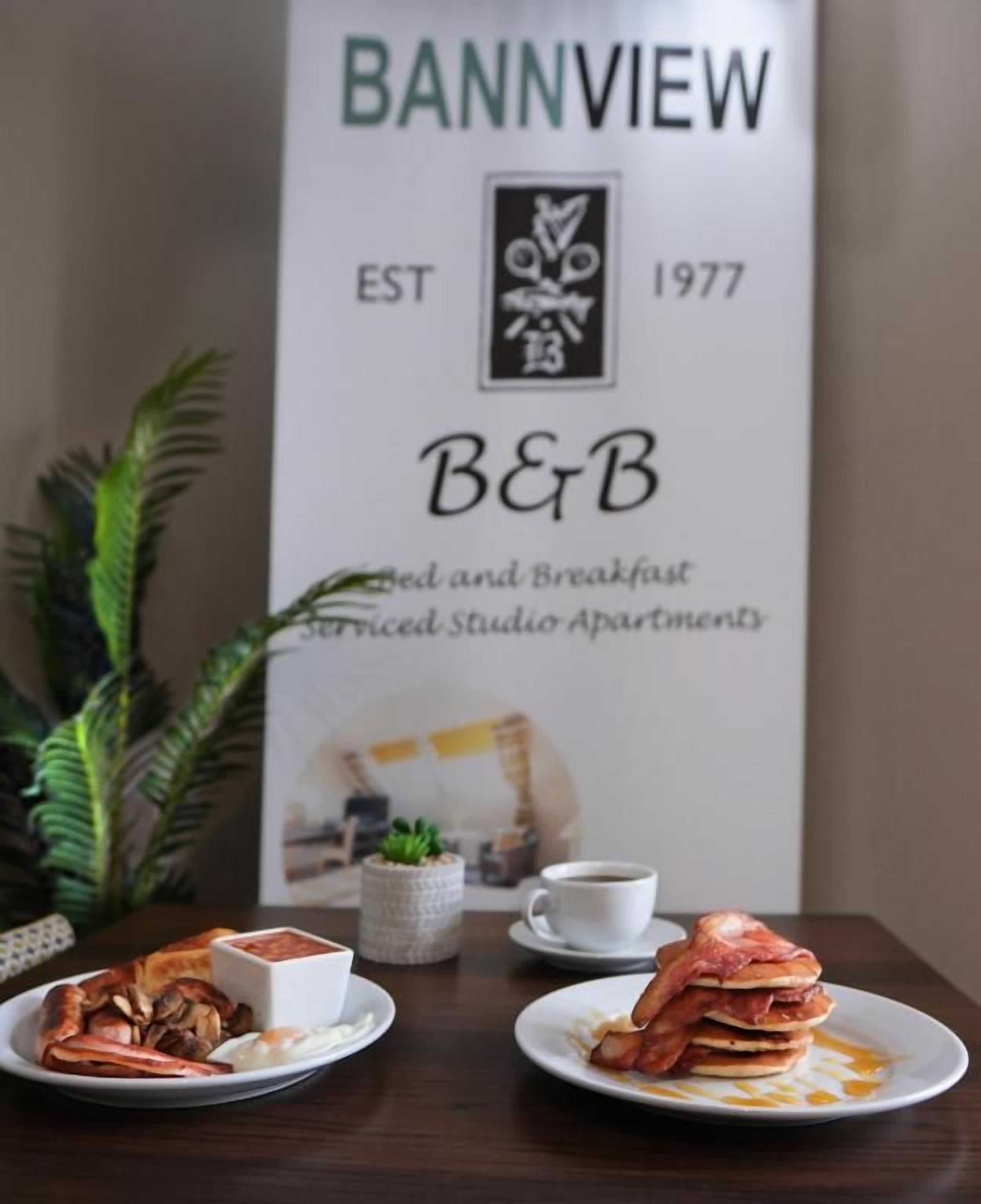 A dining table with breakfast plates, a coffee cup, and a menu board for Bannview B&B.