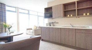 A modern kitchen with a microwave, cabinets, and a sink. There is a dining area with a table and chairs. - Bannview Bed & Breakfast (Craigavon)