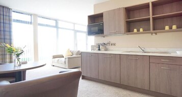 Cocina moderna con microondas, armarios y pileta. Hay un comedor con mesa y sillas.