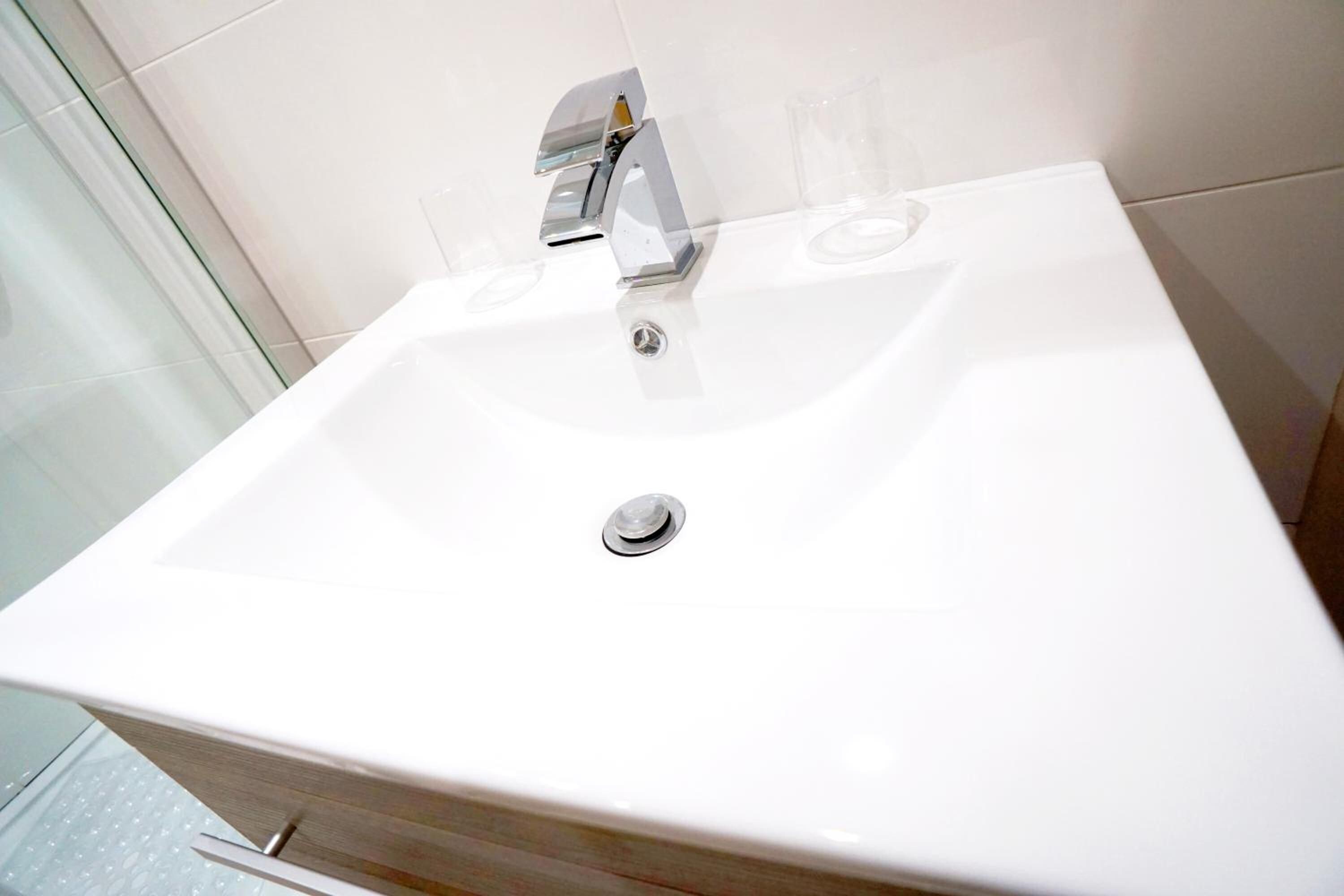 Un lavabo blanc pour la salle de bain, doté d’un robinet chromé et d’un seul miroir.