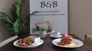 A breakfast setting with plates of food, a coffee cup, and a sign for B&B Bed and Breakfast. - Bannview Bed & Breakfast (Craigavon)